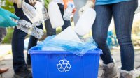 Teenagers dropping plastic bottles into recycling bin