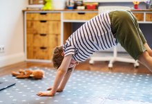 Young boy does yoga virtual class with laptop at home