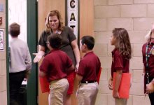 A teacher greeting her students at the door to her classroom